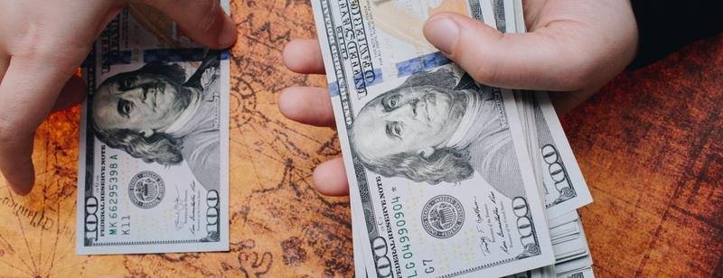 Manos contando billetes de dólares estadounidenses