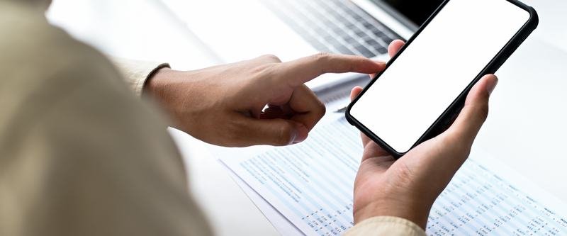 Manos sosteniendo un teléfono móvil con la pantalla en blanco