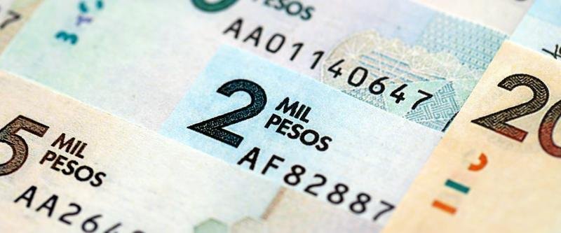 Billetes de pesos colombianos de varias denominaciones extendidos sobre una superficie